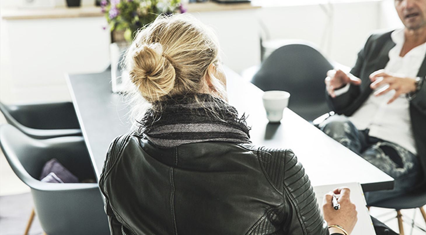 Mand og kvinde holder m�de. Kvinden tager noter.